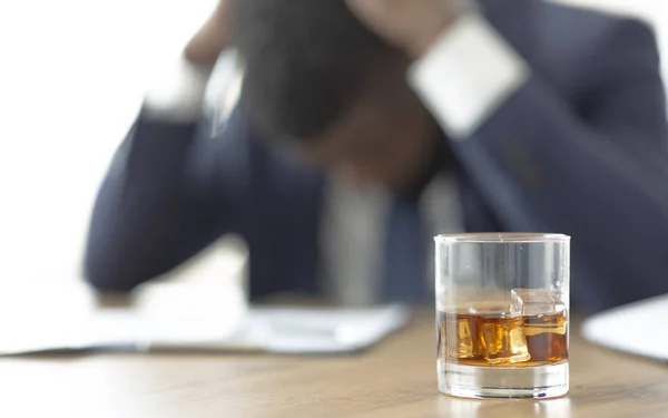 Wanhopige Afrikaanse bedrijf lijden op de werkplek met glas whisky — Stockfoto