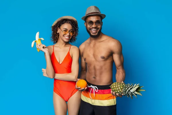 Alegre hombre negro y mujer disfrutando de frutas frescas de verano — Foto de Stock