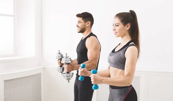 Pareja concentrada haciendo ejercicio con pesas en estudio — Foto de Stock