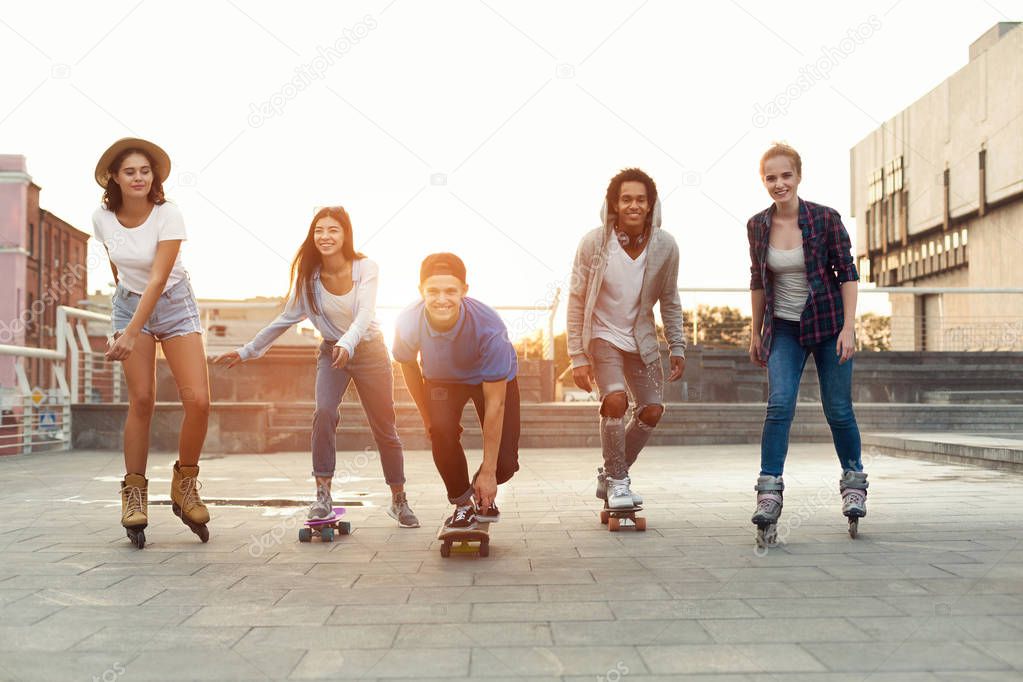 Group of smiling teenagers with roller skates and skateboard