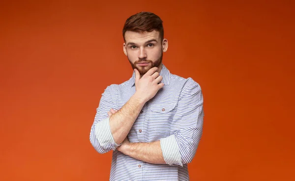 Portret van doordachte jonge man met de hand in de buurt van baard op rood — Stockfoto