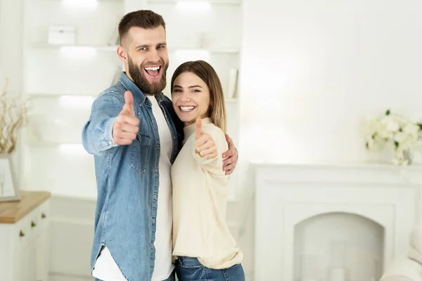 Mladý pár ukazuje palce nahoru v novém domě — Stock fotografie