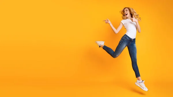 Radostná žena skákající a ukazující na místo kopírování — Stock fotografie