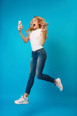 Millennial Girl Jumping ve Telefon Kullanma, Tam Uzunlukta Portre