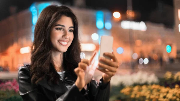 Boldog nő küld üzenetet telefonon, séta az éjszakai városban — Stock Fotó