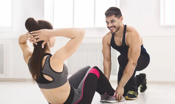 Junge Fitnesstrainerin hilft Mädchen bei Sit-Ups im Studio — Stockfoto