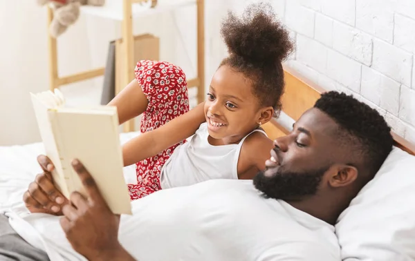 Linda chica africana escuchando cuento de hadas, papá leyendo libro a su hijo —  Fotos de Stock