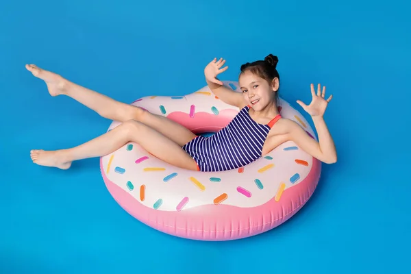 Menina pequena feliz que encontra-se no anel inflável cor-de-rosa em forma de donut — Fotografia de Stock