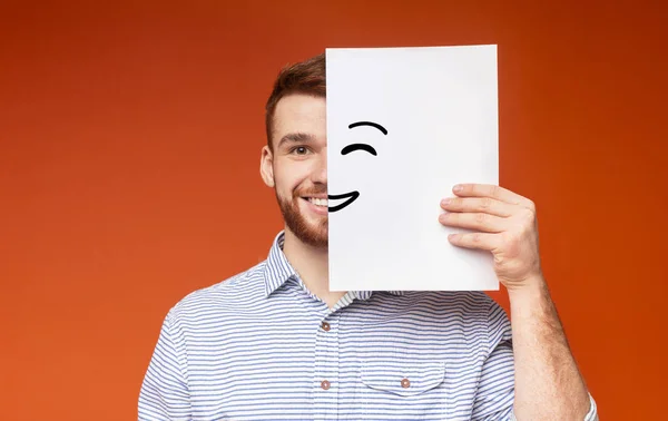 Young smiling guy supplement half of his face with painting smile — Stock Photo, Image