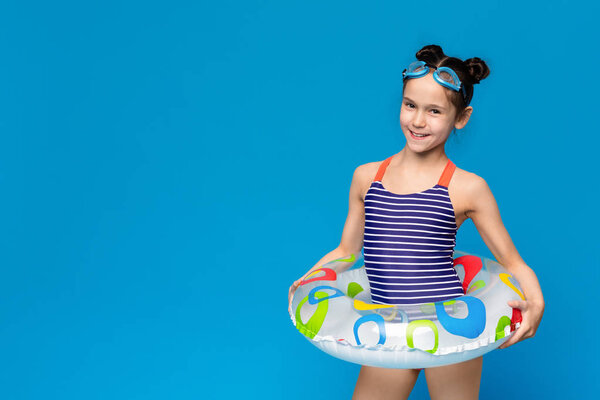 Little girl wearing inflatable ring and swim goggles