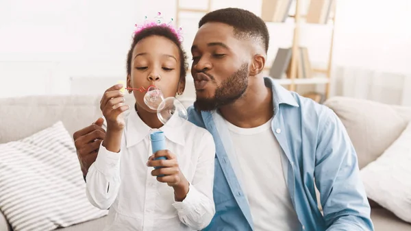 Feliz padre e hija soplando burbujas de jabón en casa — Foto de Stock