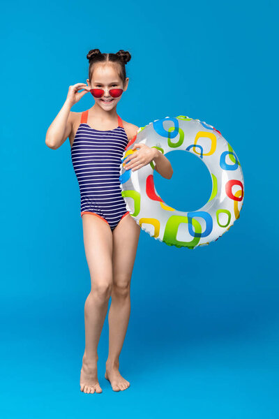 Cute girl ready for swimming, wearing swimsuit and holding inflatable ring