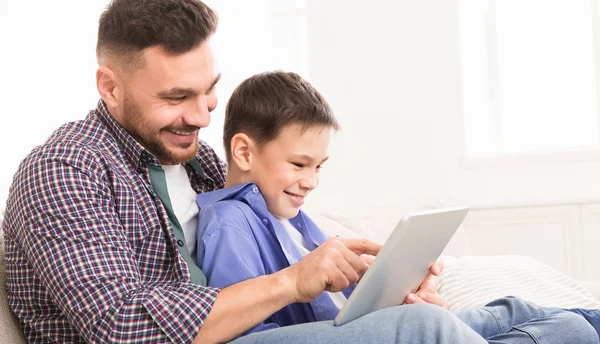 Молодой отец учит своего сына использовать специальное применение на цифровых планшетах — стоковое фото