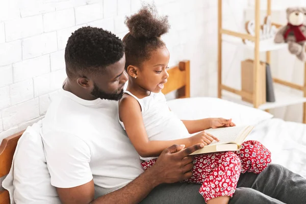 Papá africano enseñando a su hija a leer el libro —  Fotos de Stock