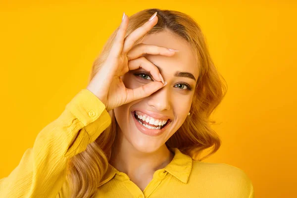 Gelukkig meisje kijken naar camera door oke gebaar — Stockfoto