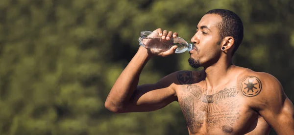 Širný svalnatý muž pitná voda po tréninku v parku — Stock fotografie