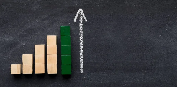 Graph of wooden blocks with arrow on chalk board — Stock Photo, Image