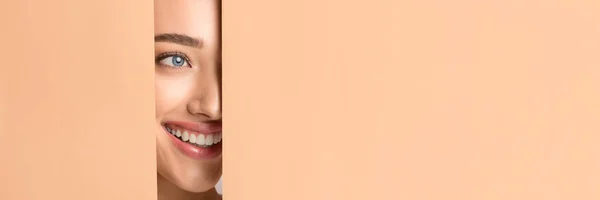 Девушка с идеальной улыбкой и голый макияж глядя в отверстие — стоковое фото