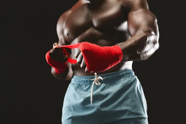 Fuerte hombre africano envolviendo las manos con envolturas de boxeo — Foto de Stock