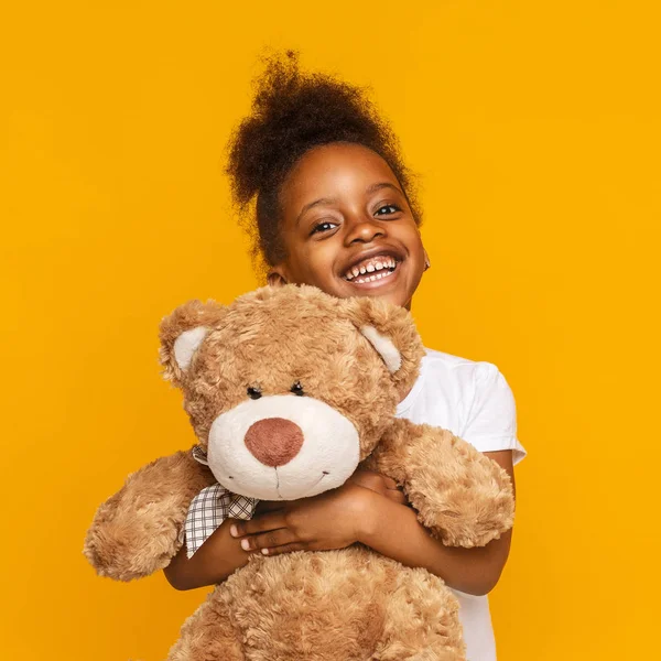 Bonito afro-americano criança abraçando ursinho de pelúcia e sorrindo — Fotografia de Stock