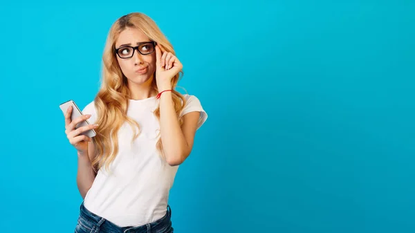 Nachdenkliche Frau hält Smartphone in der Hand und schaut weg — Stockfoto