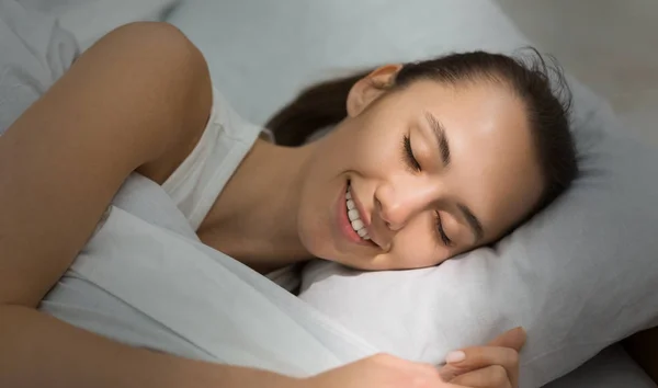 Ευχάριστος ύπνος. Κορίτσι που κοιμάται στο κρεβάτι με ηλιακή ακτίνα στο πρόσωπο — Φωτογραφία Αρχείου