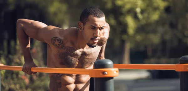 Muskulös kille gör Street workout, utövar på parallella barer — Stockfoto