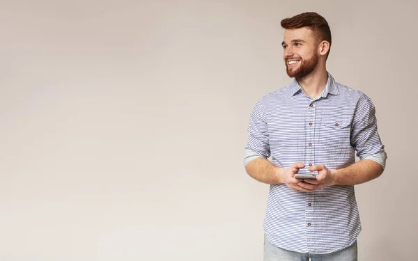 Joven blogger usando su teléfono y mirando hacia otro lado — Foto de Stock