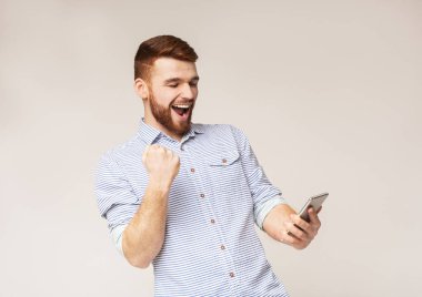 Evet işareti gösteren ve telefonuna bakarak neşeli adam