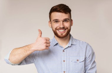 Genç adam gösteren başparmak yukarı ve gülümsüyor üzerinde kamera