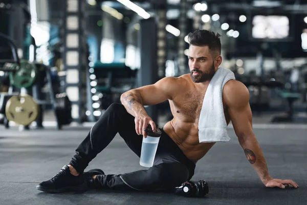 Homem muscular concentrado água potável no ginásio — Fotografia de Stock