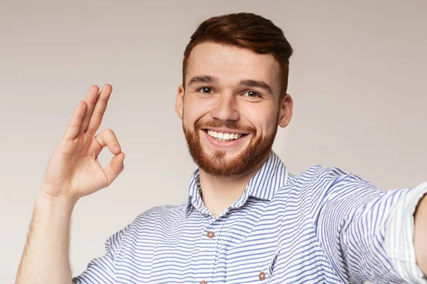 Guapo chico mostrando OK signo y haciendo selfie — Foto de Stock