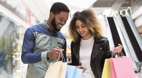 Gelukkige Afrikaanse man toont zijn vriendin aankopen — Stockfoto