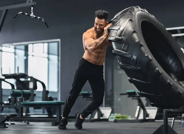Hombre desnudo volteando enorme neumático en el gimnasio —  Fotos de Stock