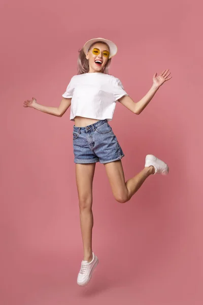 Moda menina pulando no fundo rosa, estilo adolescente de verão — Fotografia de Stock