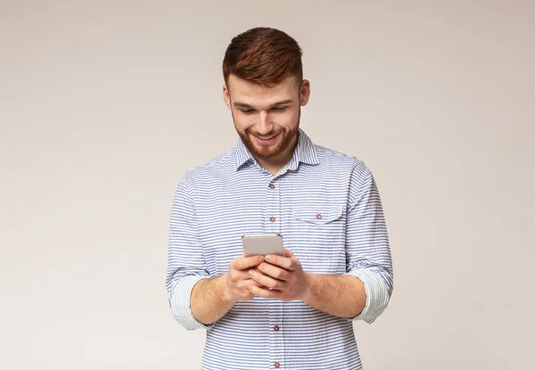 Молодий чоловік поглинає текстові повідомлення на мобільному телефоні — стокове фото