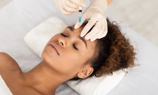 Kosmetikerin injizierte Botox in weibliche Stirn — Stockfoto