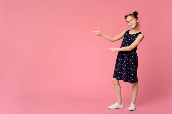 Menina alegre em vestido elegante apontando para o espaço vazio — Fotografia de Stock