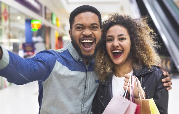 Gelukkige Afrikaanse paar maken selfie in Mall met tassen — Stockfoto