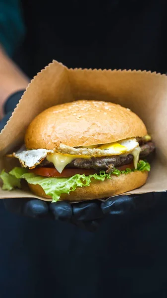 Duży Hamburger z stek i jaj z bliska w ręce kucharzy — Zdjęcie stockowe