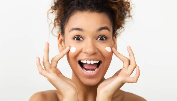 Cuidado de la piel. Mujer emocionada aplicando crema facial — Foto de Stock