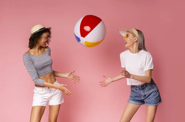 Playful girls in summer wear playing with big beach ball