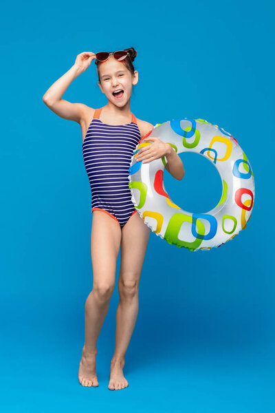 Cheerful little girl in swimsuit enjoying summer time with inflatable ring
