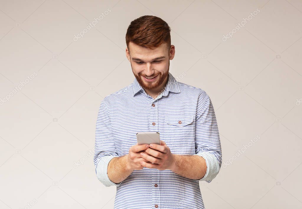 Young man absorbedly text messaging on his cellphone