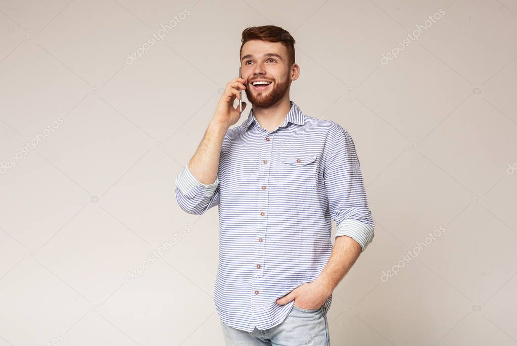 Cheerful man using his phone and widely smiling