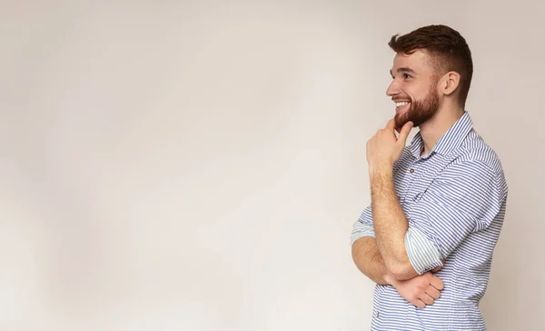 Giovane uomo sorridente che pensa e distoglie lo sguardo sullo spazio libero — Foto Stock