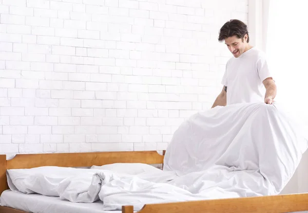 Тысячелетний парень, делающий постель по утрам, домашняя рутина — стоковое фото