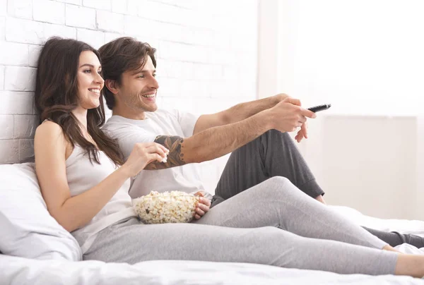 Мужчина и женщина влюблены, смотрят фильм с попкорном в постели — стоковое фото