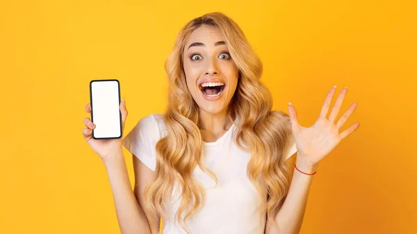 Nueva aplicación. Mujer emocional mostrando pantalla de teléfono inteligente en blanco — Foto de Stock