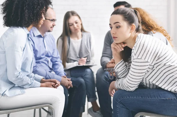 Stressed thoughtful woman during group rehab therapy